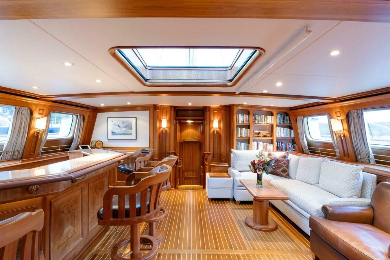 The yacht's salon features elegant wood paneling, comfortable seating, and ample natural light from large windows and a skylight. aboard CATALINA Yacht for Sale
