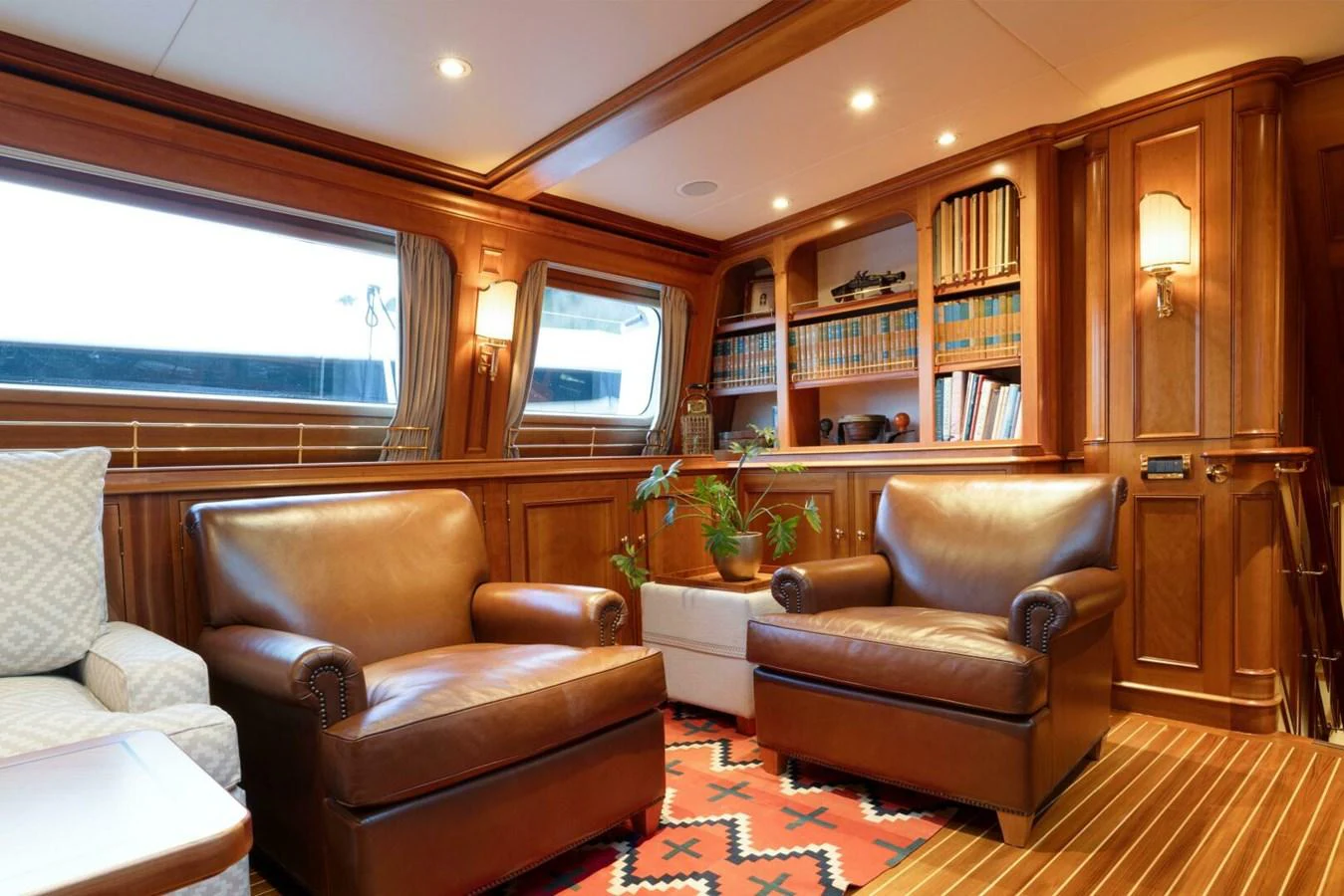 The yacht's salon features luxurious leather armchairs, wooden paneling, and a well-stocked bookshelf, creating a warm and inviting atmosphere. aboard CATALINA Yacht for Sale