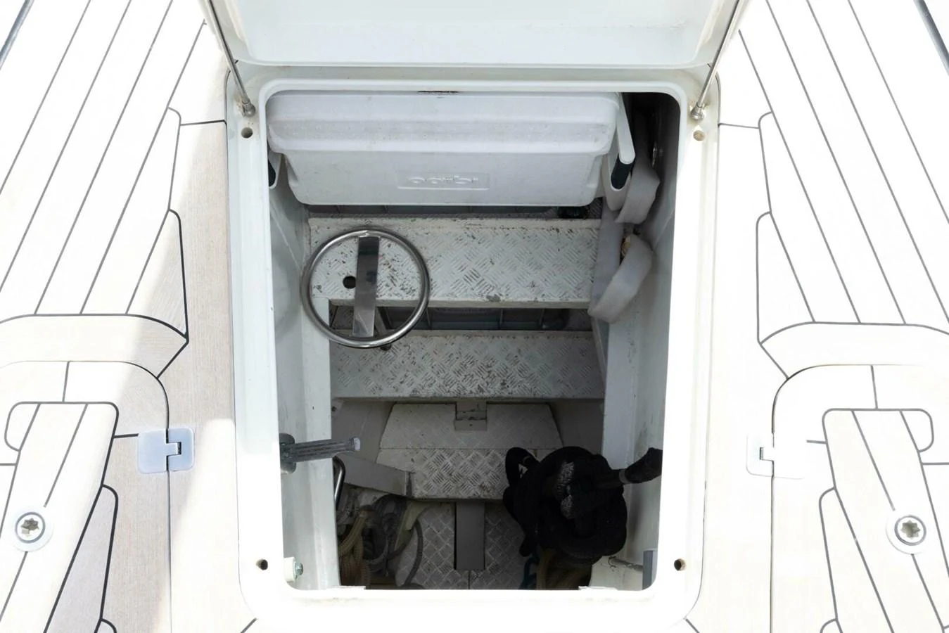 A view into a storage compartment with a steering wheel and various equipment. aboard CATALINA Yacht for Sale