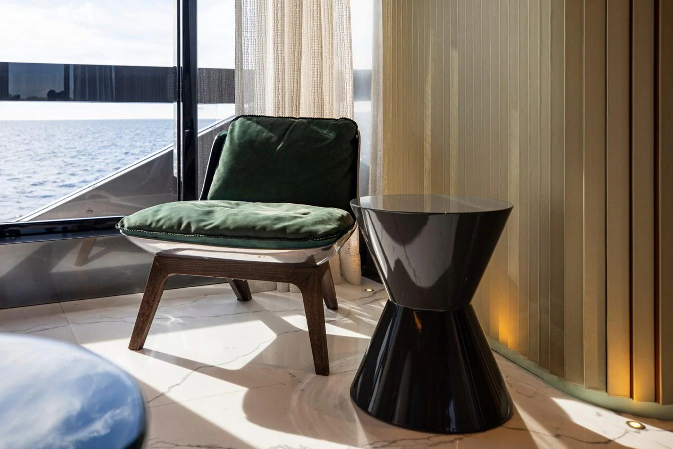 A cozy seating area with a modern chair and side table, offering a serene view of the sea. aboard PACIFIC PEARL Yacht for Sale