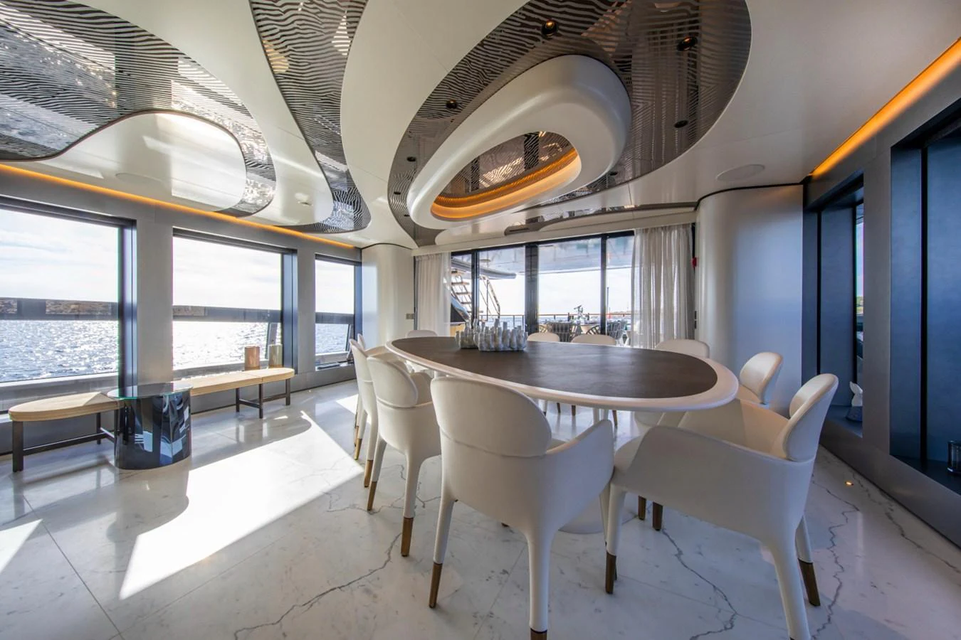 The yacht's dining area features elegant seating and a stunning view through large windows. aboard PACIFIC PEARL Yacht for Sale