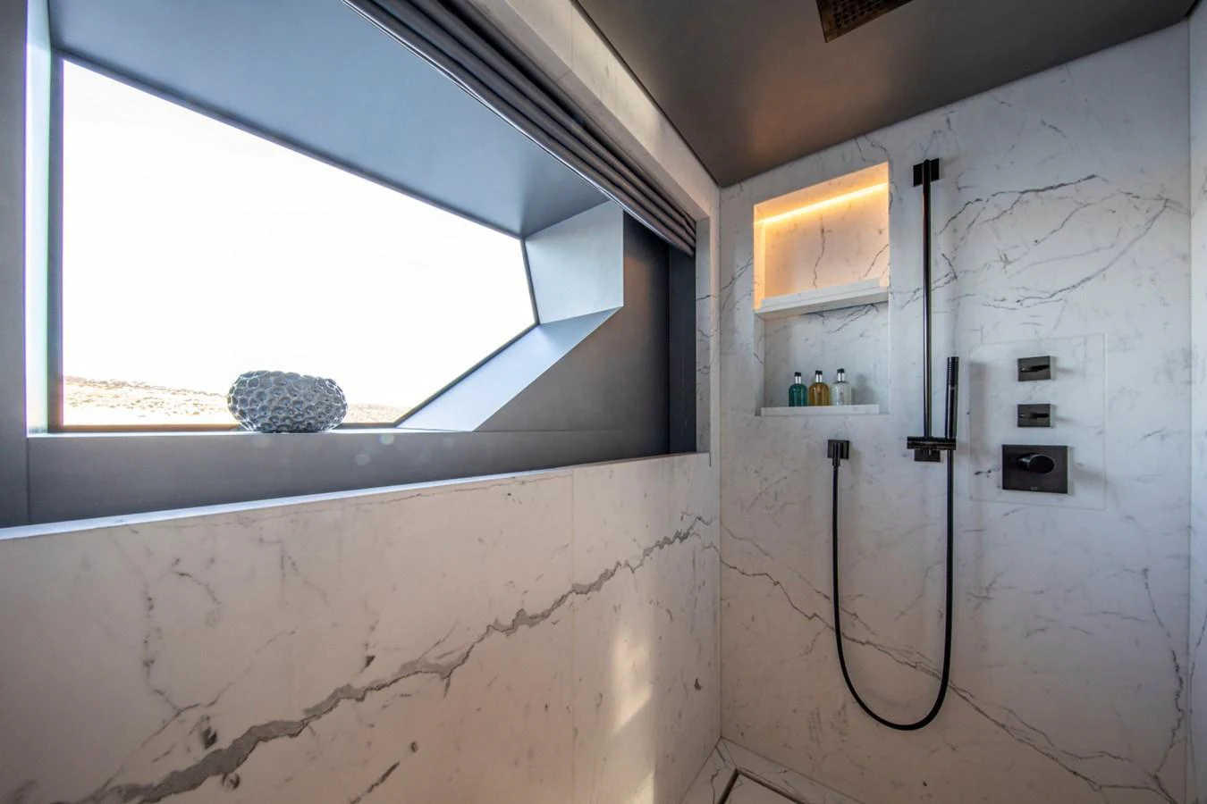 The yacht's bathroom features a sleek, modern design with marble walls and a large window for natural light. aboard PACIFIC PEARL Yacht for Sale