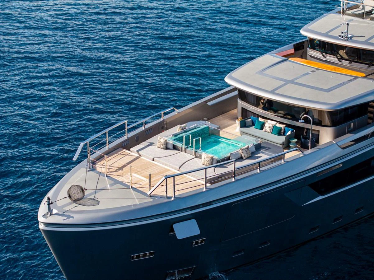 The yacht's foredeck features a luxurious pool area with ample lounging space, set against the backdrop of the open sea. aboard PACIFIC PEARL Yacht for Sale