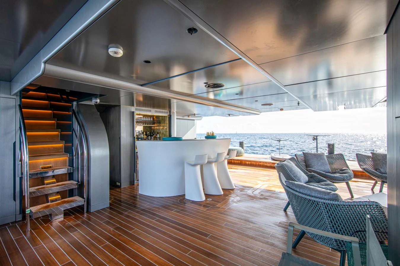 The aft deck features a stylish bar area with modern seating and a stunning ocean view. aboard PACIFIC PEARL Yacht for Sale
