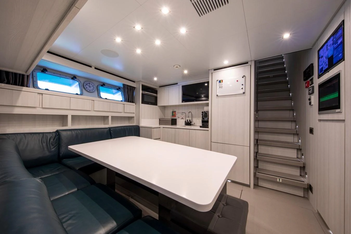 The yacht's interior dining area features a sleek table surrounded by comfortable seating, illuminated by modern lighting. aboard PACIFIC PEARL Yacht for Sale