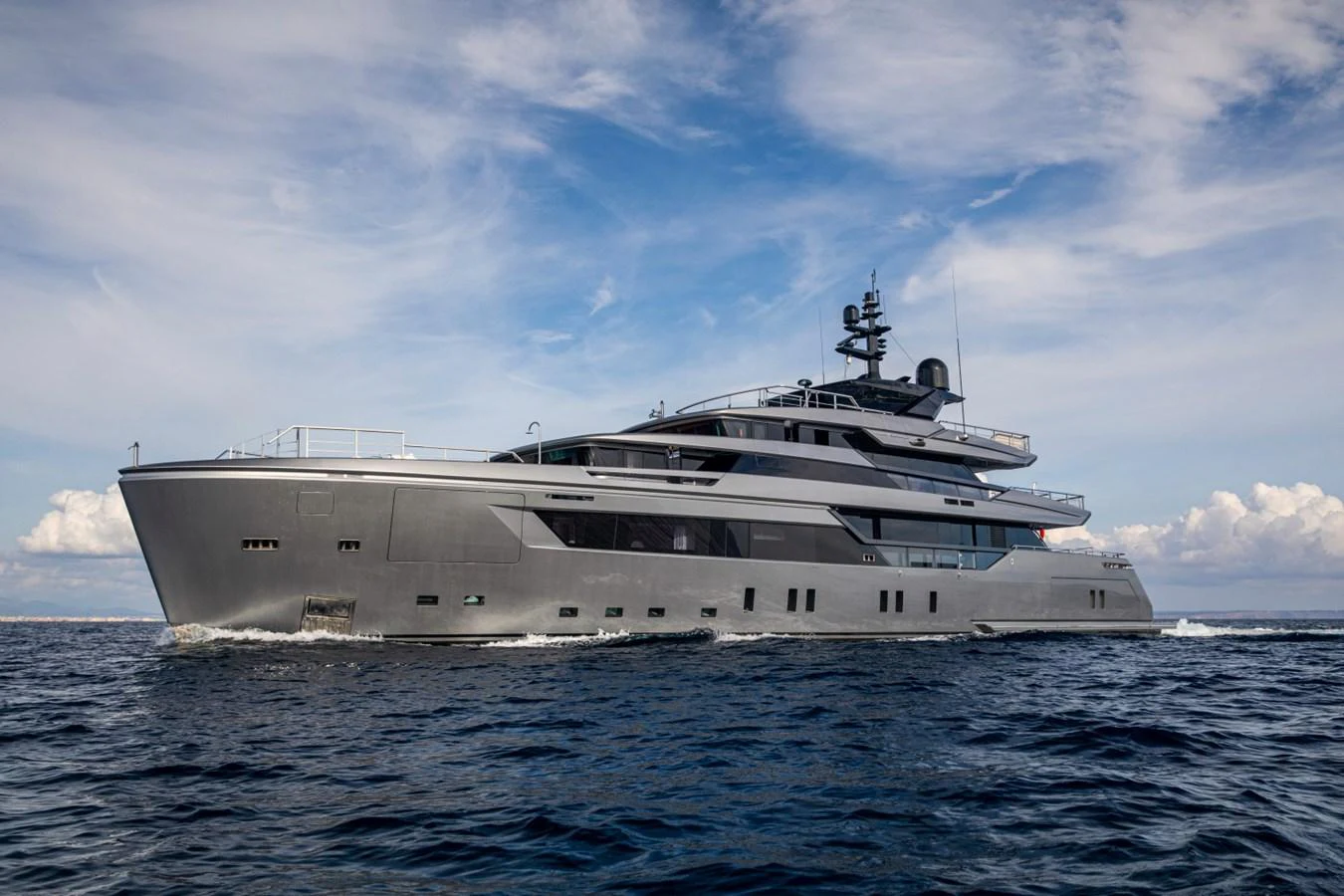 A sleek and modern yacht cruising on the open sea under a partly cloudy sky. aboard PACIFIC PEARL Yacht for Sale