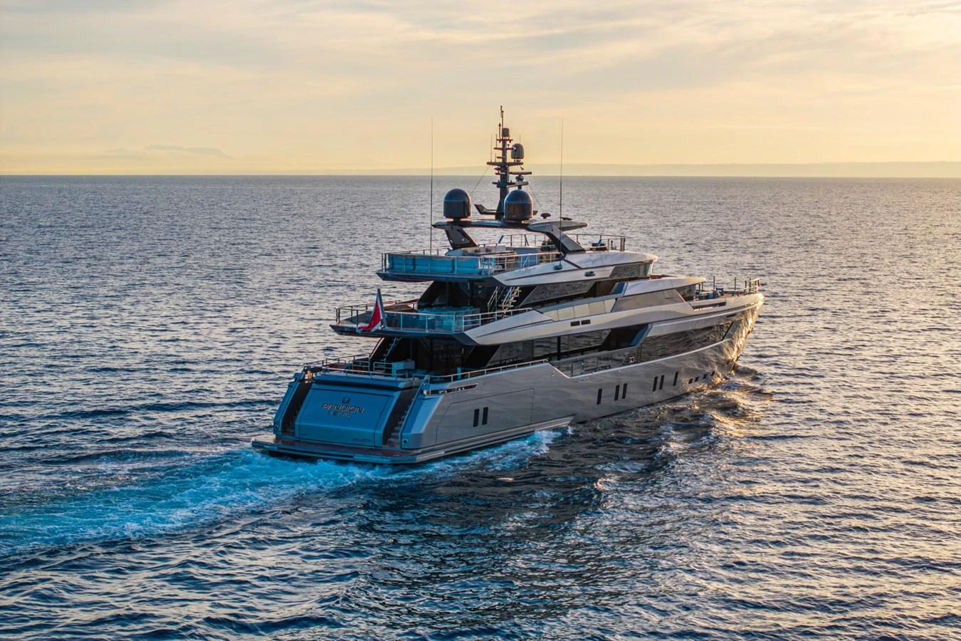 A luxurious yacht cruises through the open sea at sunset, showcasing its sleek design and modern amenities. aboard PACIFIC PEARL Yacht for Sale