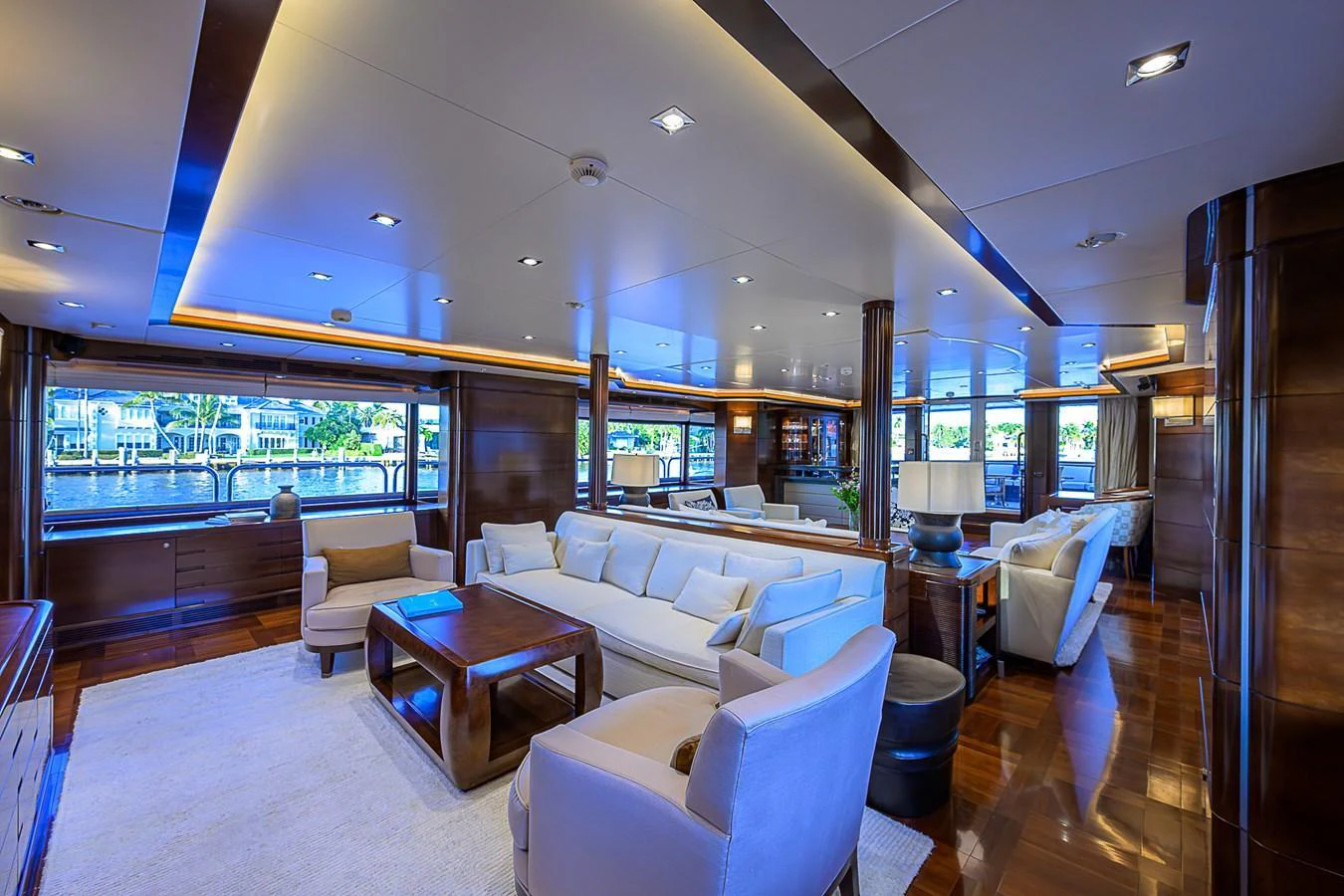 The spacious salon features luxurious seating and panoramic windows with a serene waterfront view. aboard SEASCAPE V Yacht for Sale