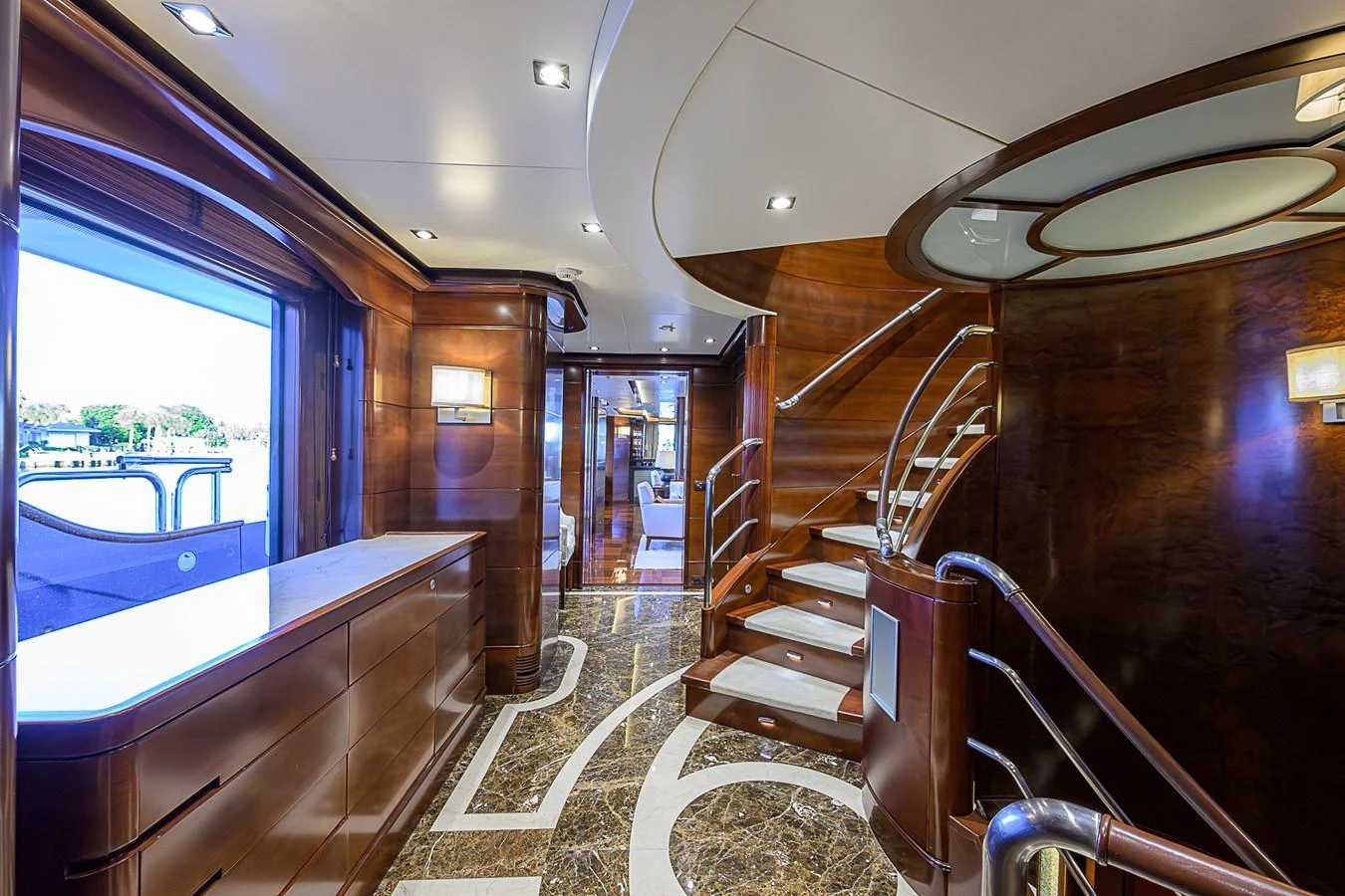 The yacht's interior features a luxurious staircase with elegant wood paneling and marble flooring. aboard SEASCAPE V Yacht for Sale
