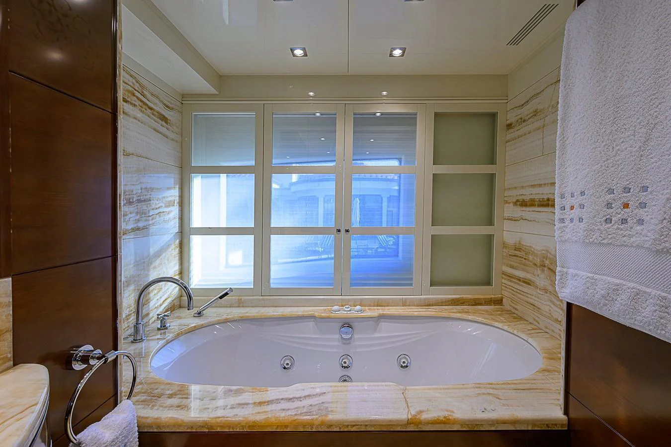The luxurious bathroom features a large soaking tub with elegant marble surroundings and a serene view through frosted windows. aboard SEASCAPE V Yacht for Sale