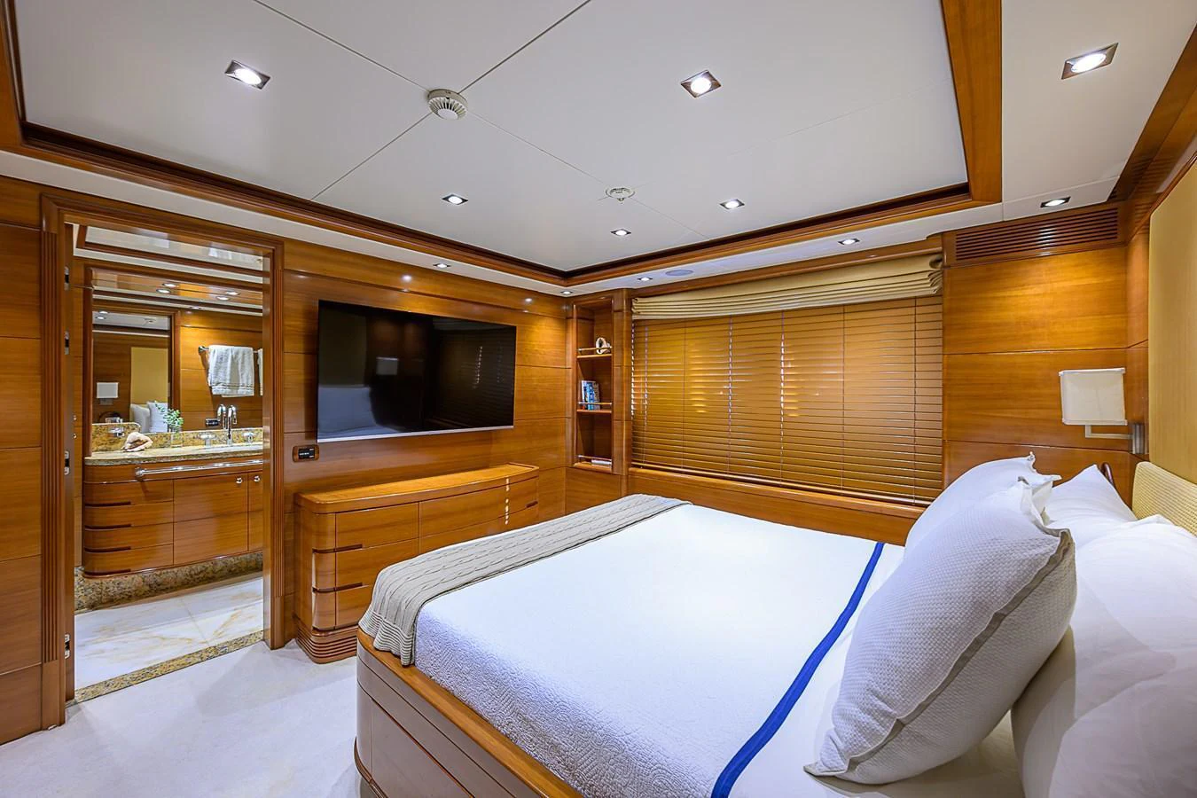 The master stateroom features a luxurious bed, elegant wood finishes, and a large flat-screen TV. aboard SEASCAPE V Yacht for Sale