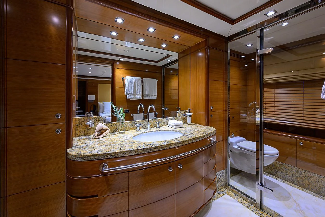 The yacht's bathroom features luxurious wood paneling and a spacious vanity with elegant fixtures. aboard SEASCAPE V Yacht for Sale