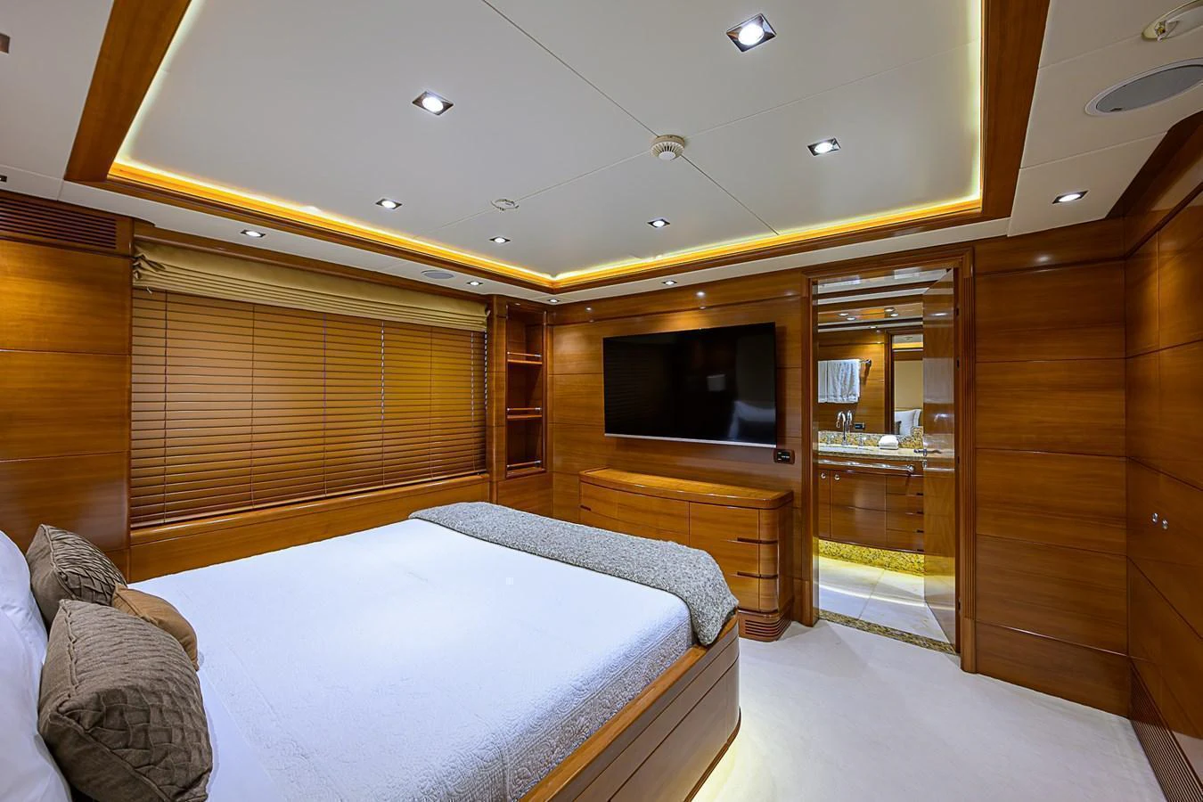 The master stateroom features a luxurious bed, wood paneling, and a large flat-screen TV. aboard SEASCAPE V Yacht for Sale
