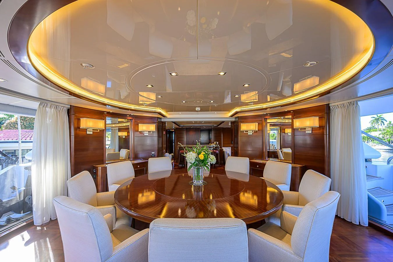 The yacht's dining area features a large round table surrounded by plush chairs, set under a beautifully lit ceiling. aboard SEASCAPE V Yacht for Sale