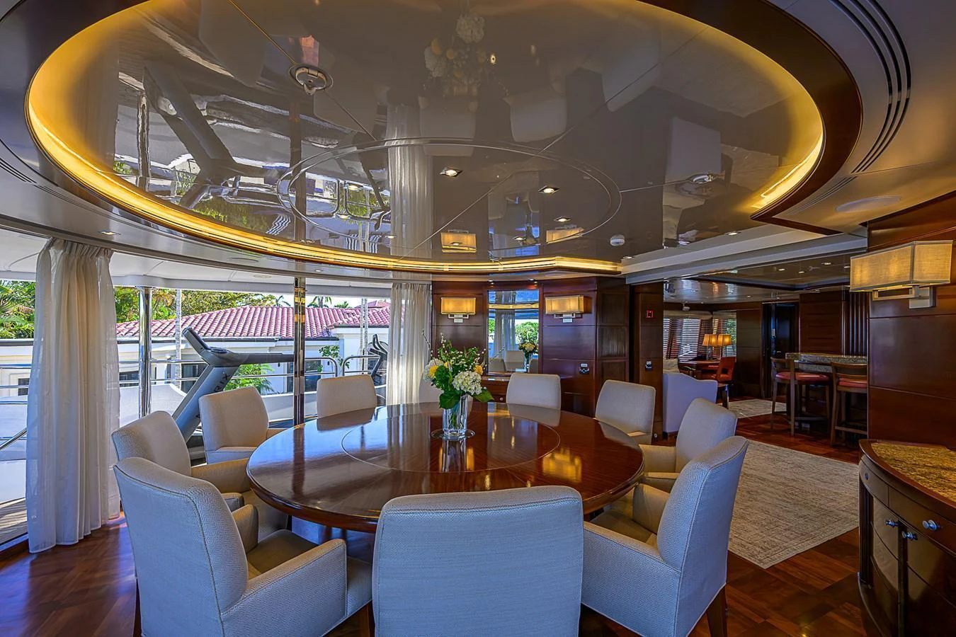 The yacht's dining area features a large round table surrounded by plush chairs, with elegant lighting and a reflective ceiling. aboard SEASCAPE V Yacht for Sale