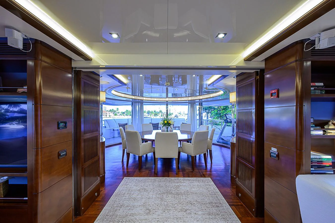 The yacht's interior dining area features elegant wooden finishes and a view of the exterior deck. aboard SEASCAPE V Yacht for Sale