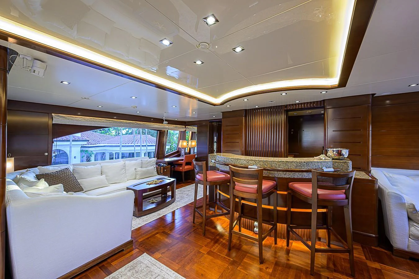 The yacht's salon features a spacious seating area with plush white sofas and a stylish bar with high stools. aboard SEASCAPE V Yacht for Sale