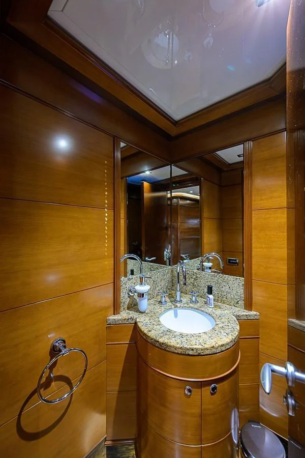 A luxurious yacht bathroom featuring a granite countertop and wooden paneling. aboard SEASCAPE V Yacht for Sale