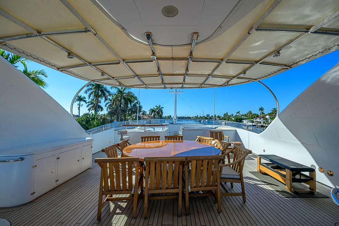The sundeck features a spacious dining area with a large wooden table and chairs under a canopy. aboard SEASCAPE V Yacht for Sale