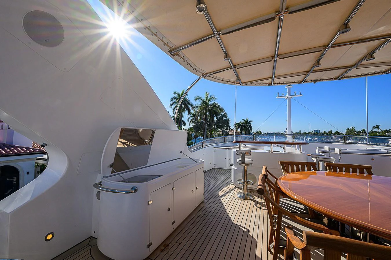 The aft deck features a spacious dining area under a shaded canopy, perfect for enjoying meals with a view. aboard SEASCAPE V Yacht for Sale