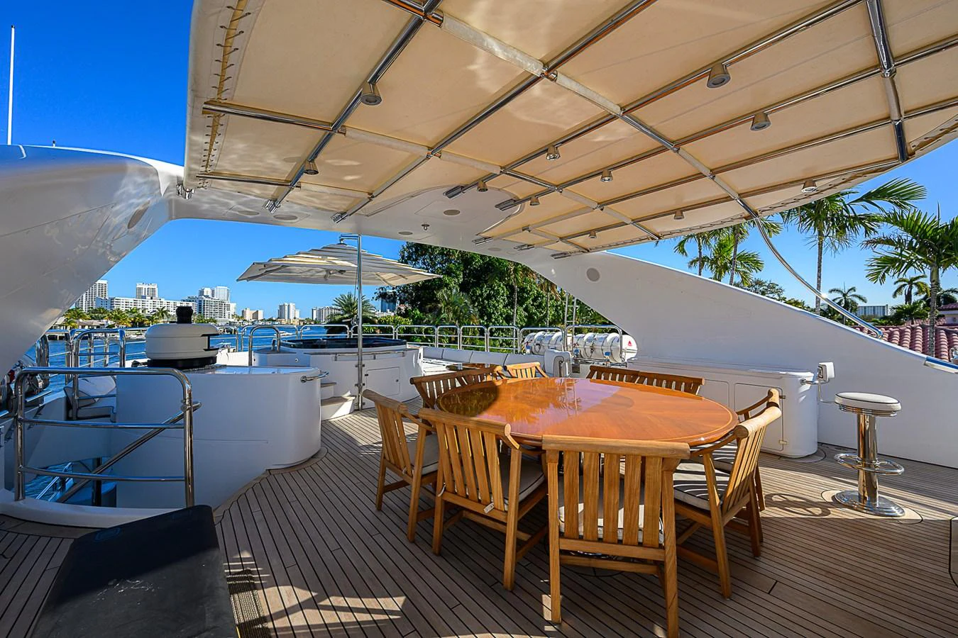 The aft deck features a spacious dining area with a large wooden table and comfortable chairs, perfect for alfresco dining. aboard SEASCAPE V Yacht for Sale