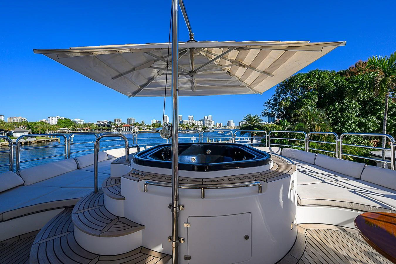 The sundeck features a luxurious hot tub shaded by a large umbrella, offering stunning views of the surrounding waters. aboard SEASCAPE V Yacht for Sale