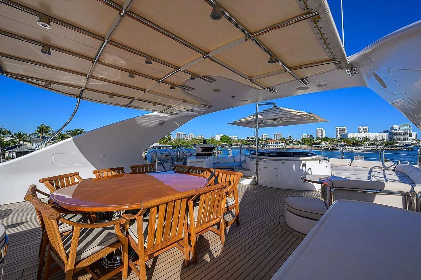 The aft deck features a spacious dining area with a large wooden table and comfortable seating, perfect for alfresco dining. aboard SEASCAPE V Yacht for Sale