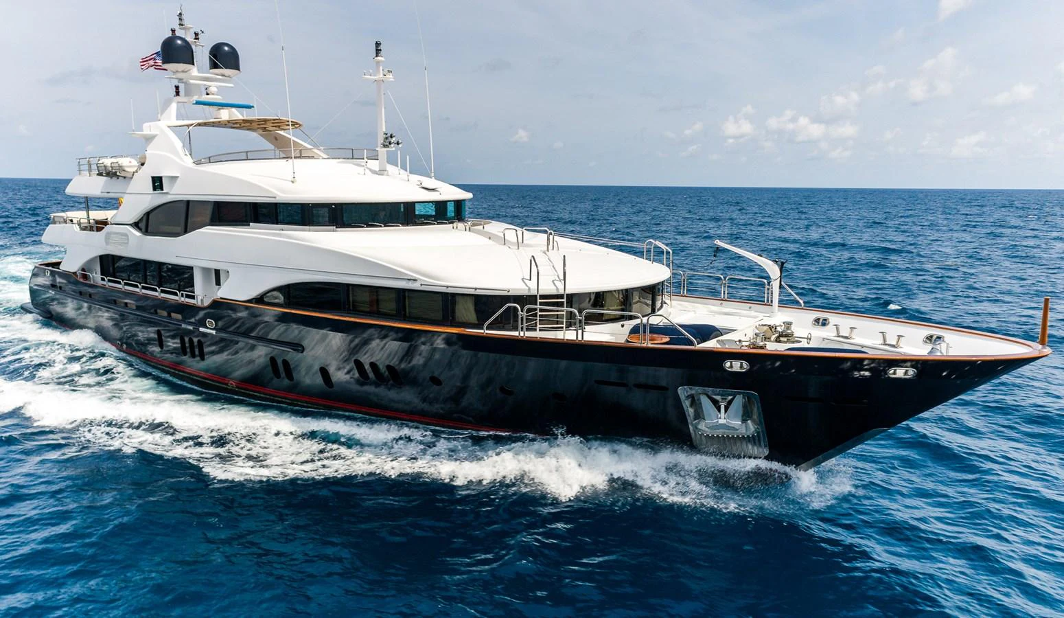 A sleek and modern yacht cruising through open waters under a clear sky. aboard SEASCAPE V Yacht for Sale