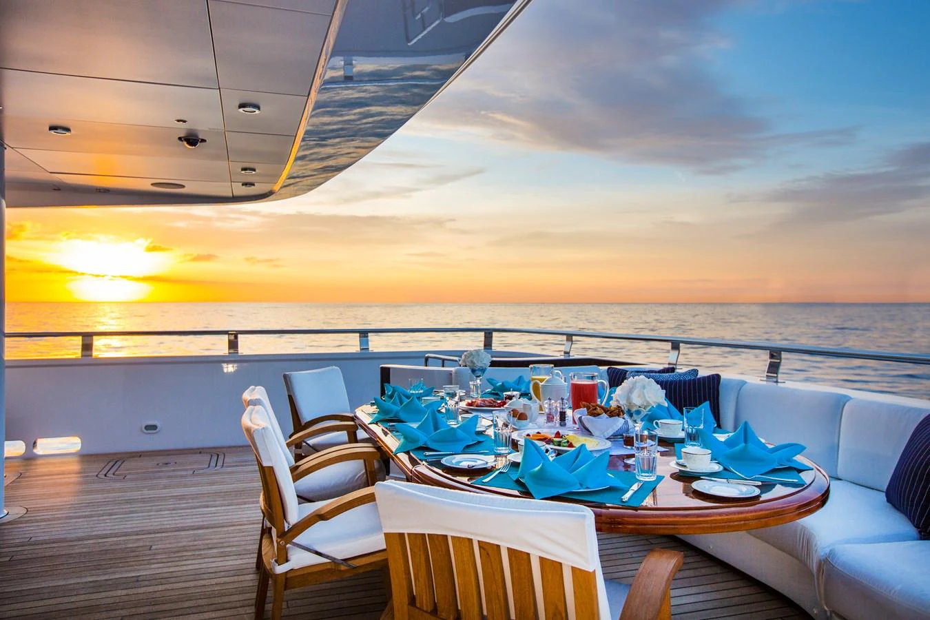An elegant dining setup on the aft deck with a stunning sunset view over the ocean. aboard ALASKA OF GEORGE TOWN Yacht for Sale