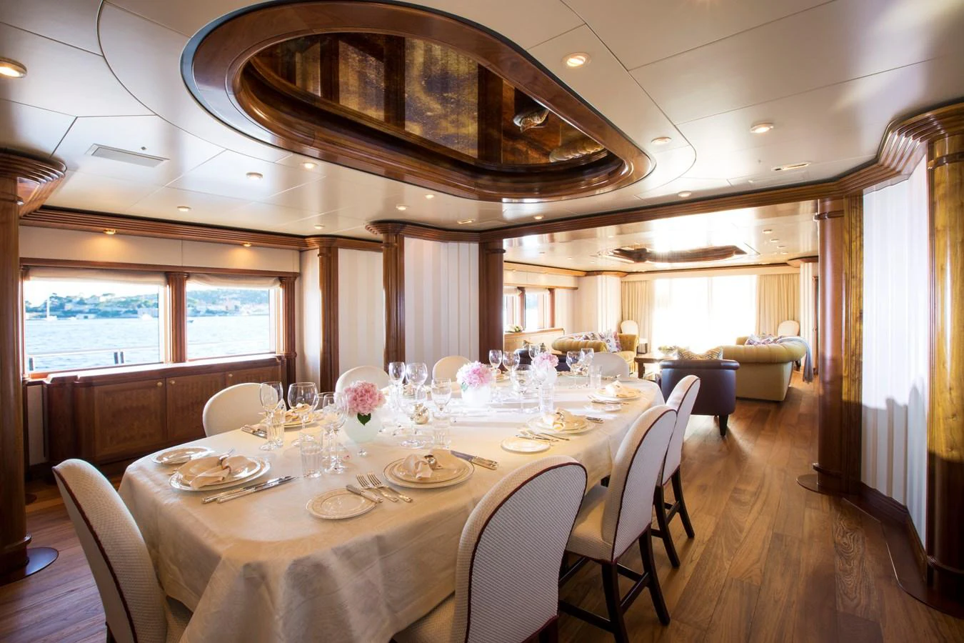 The yacht's dining area features an elegant table setting with a view of the water through large windows. aboard ALASKA OF GEORGE TOWN Yacht for Sale