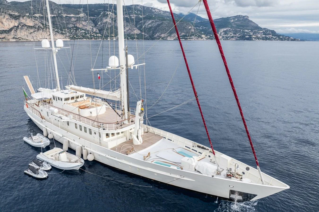 A majestic sailing yacht glides through calm waters with a stunning coastal backdrop. aboard DIONE STAR Yacht for Sale