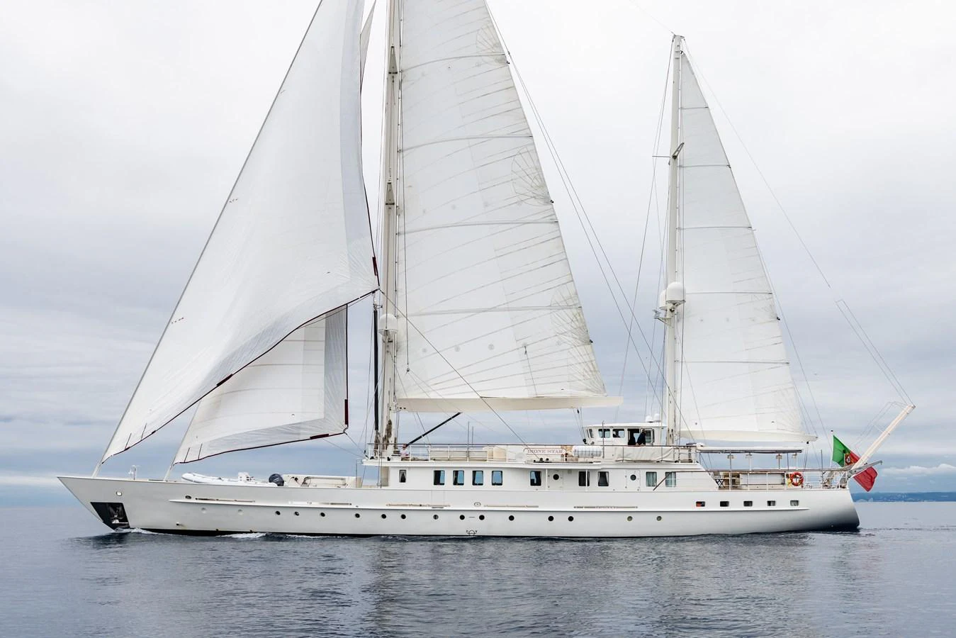 A majestic sailing yacht glides gracefully on calm waters under a cloudy sky. aboard DIONE STAR Yacht for Sale