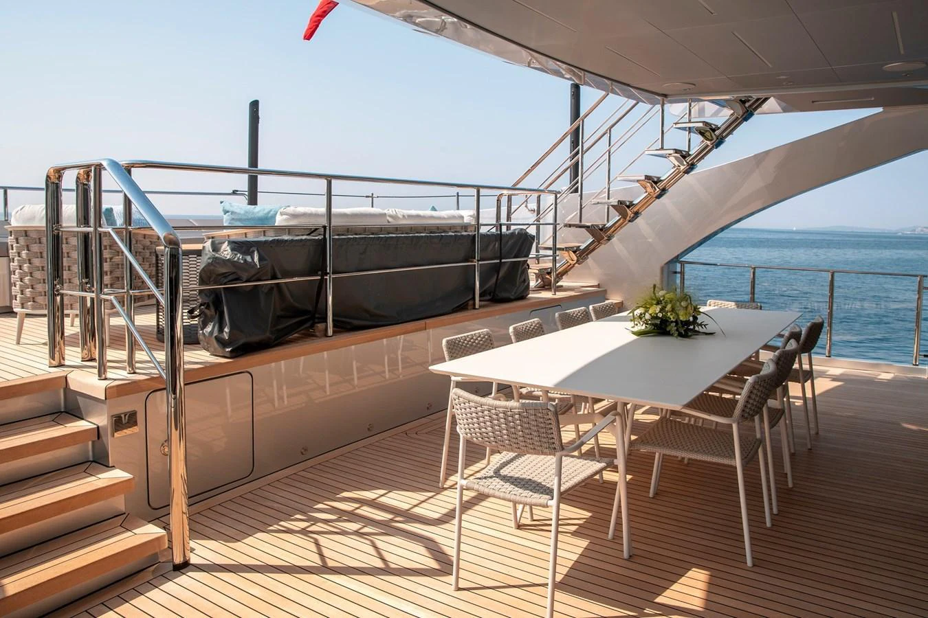 The aft deck features a spacious dining area with a modern table and comfortable seating, perfect for alfresco meals with a view of the sea. aboard PERSHING 140 Yacht for Sale