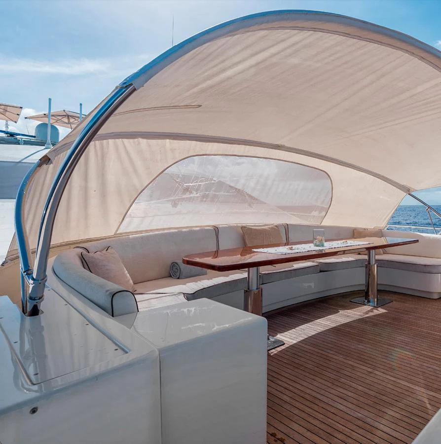 The aft deck features a comfortable seating area with a wooden table under a shaded canopy. aboard ANTELOPE IV Yacht for Sale