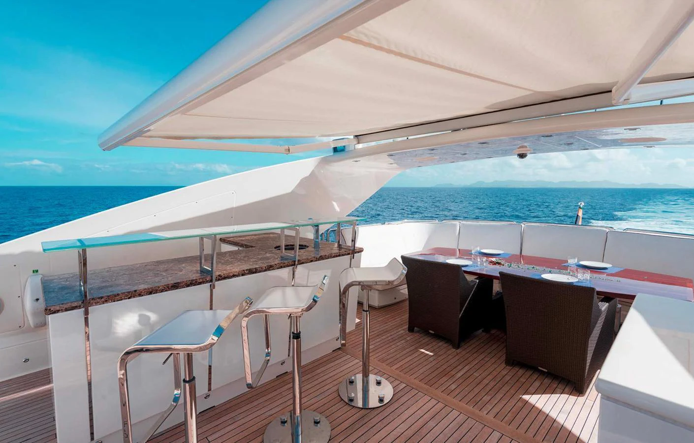 The flybridge features a stylish bar area with modern seating and a dining table, all under a retractable canopy. aboard ANTELOPE IV Yacht for Sale