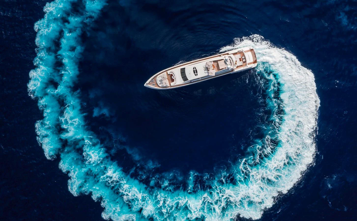 A stunning aerial view of a yacht creating a circular wake in the deep blue sea. aboard ANTELOPE IV Yacht for Sale