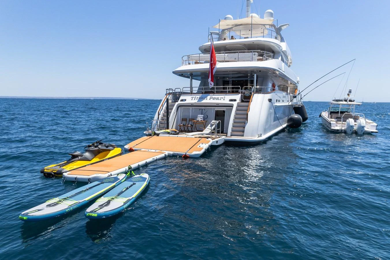 The yacht's aft deck features a spacious swim platform with paddleboards and a jet ski ready for water activities. aboard TITIAN PEARL Yacht for Sale
