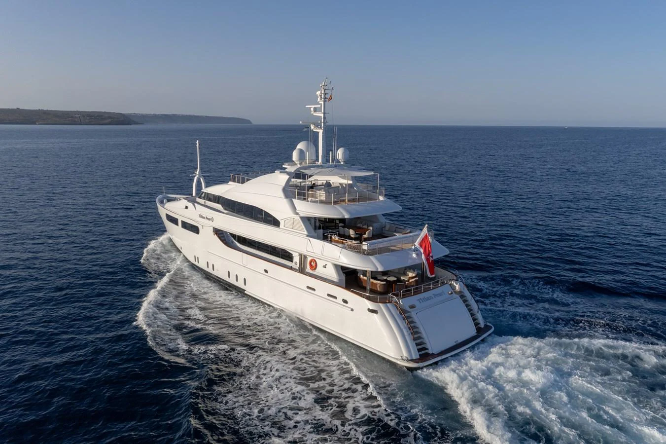 A luxurious yacht cruises through calm waters under a clear sky. aboard TITIAN PEARL Yacht for Sale
