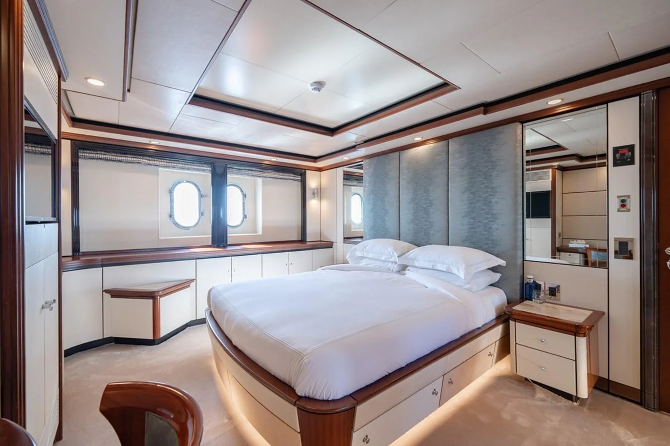 The master stateroom features a spacious bed, elegant wood finishes, and ample natural light. aboard TITIAN PEARL Yacht for Sale