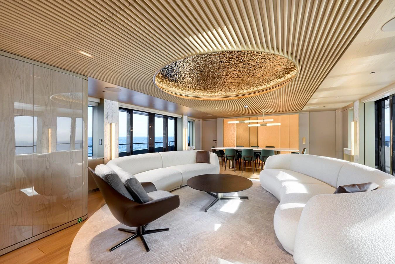 The salon features a modern design with a large circular sofa and a stunning ceiling detail. aboard XIMENA Yacht for Sale