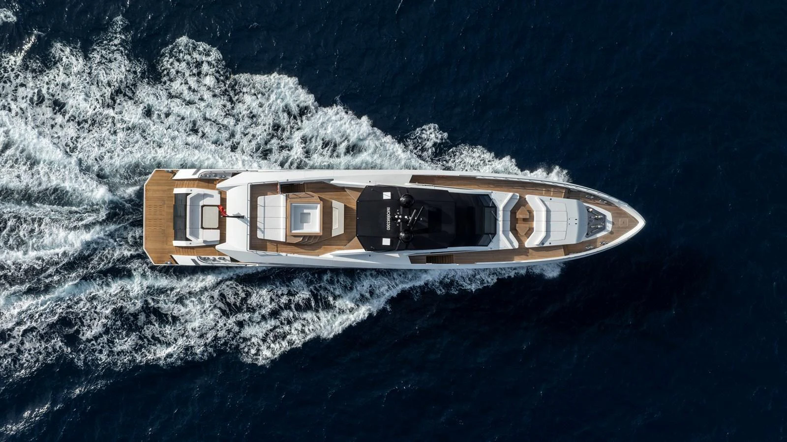 An aerial view of a sleek yacht cruising through the water, showcasing its elegant design and spacious deck areas. aboard XIMENA Yacht for Sale