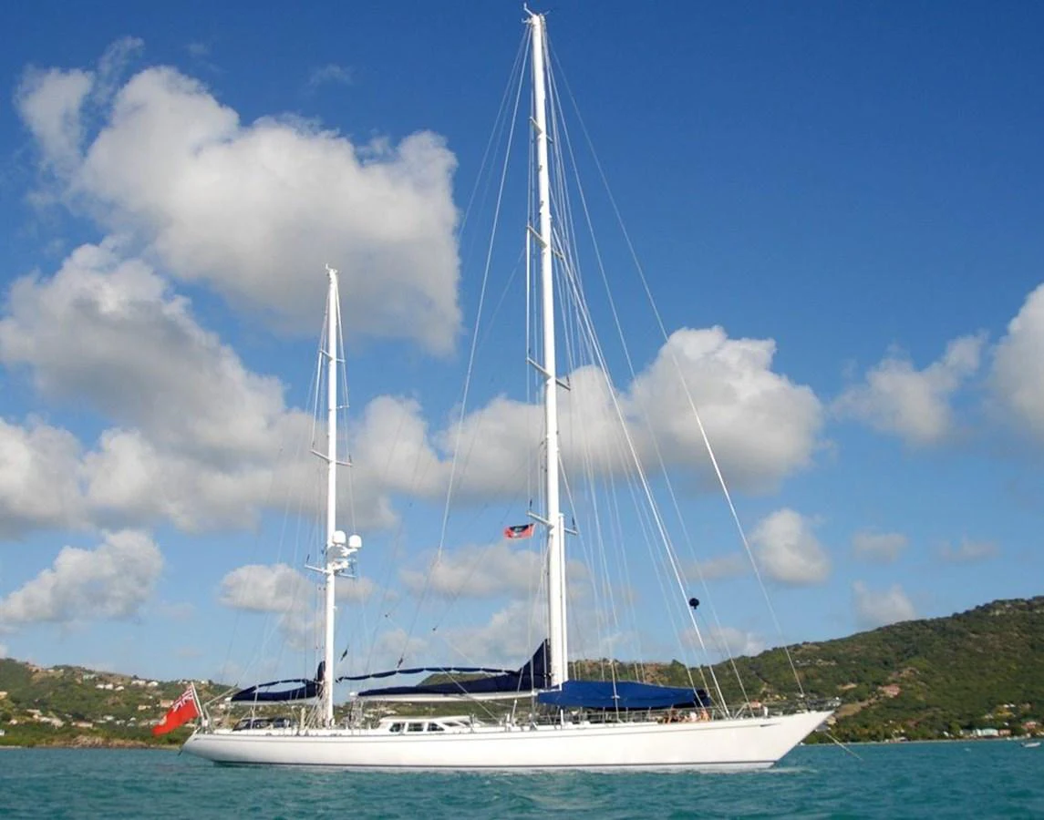 A sleek sailing yacht glides gracefully on turquoise waters under a clear blue sky. aboard CYCLOS III Yacht for Sale