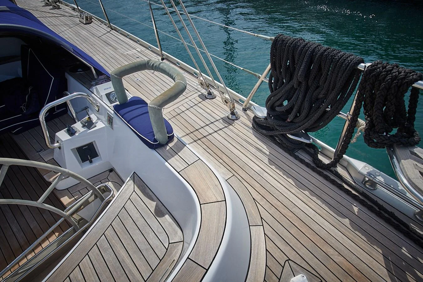 The image showcases a well-maintained teak deck with neatly coiled ropes and polished metal fittings. aboard CYCLOS III Yacht for Sale