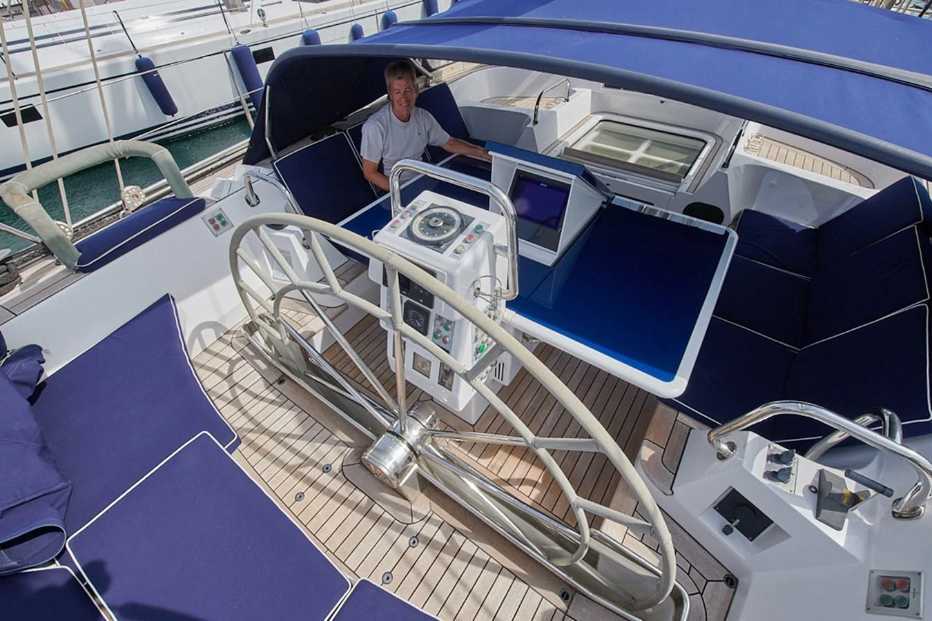 The yacht's cockpit features a spacious seating area with blue cushions and a helm station under a blue canopy. aboard CYCLOS III Yacht for Sale