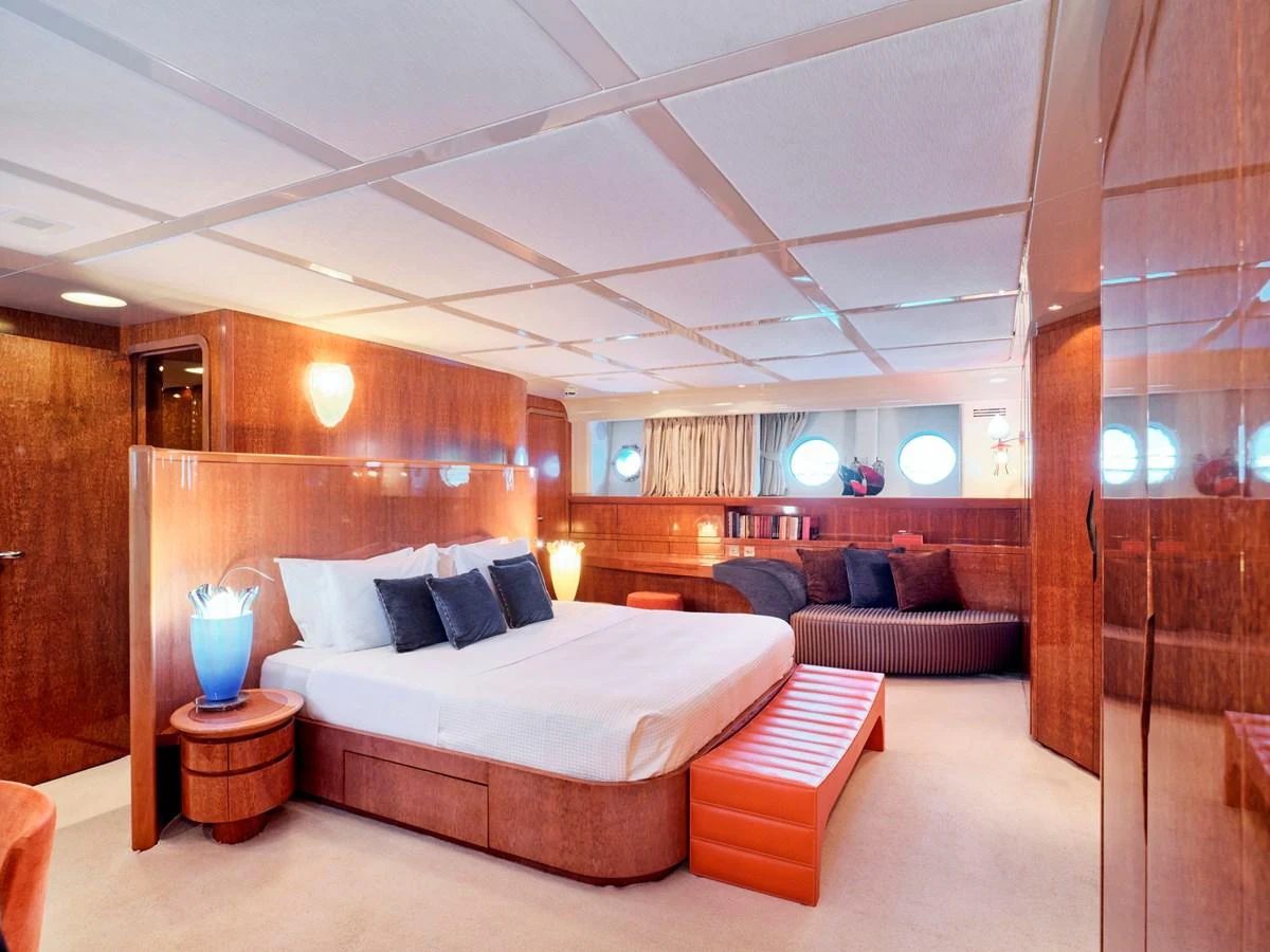 The master stateroom features a spacious bed, elegant wood paneling, and ambient lighting. aboard CONDOR A Yacht for Sale