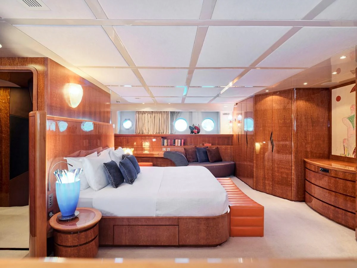 The master stateroom features a luxurious bed, elegant wood finishes, and ambient lighting. aboard CONDOR A Yacht for Sale