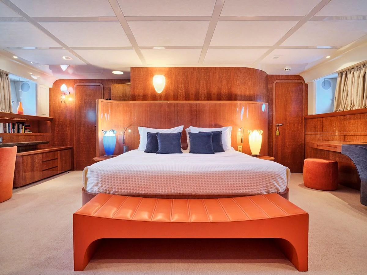 The master stateroom features a luxurious bed with elegant wood paneling and ambient lighting. aboard CONDOR A Yacht for Sale