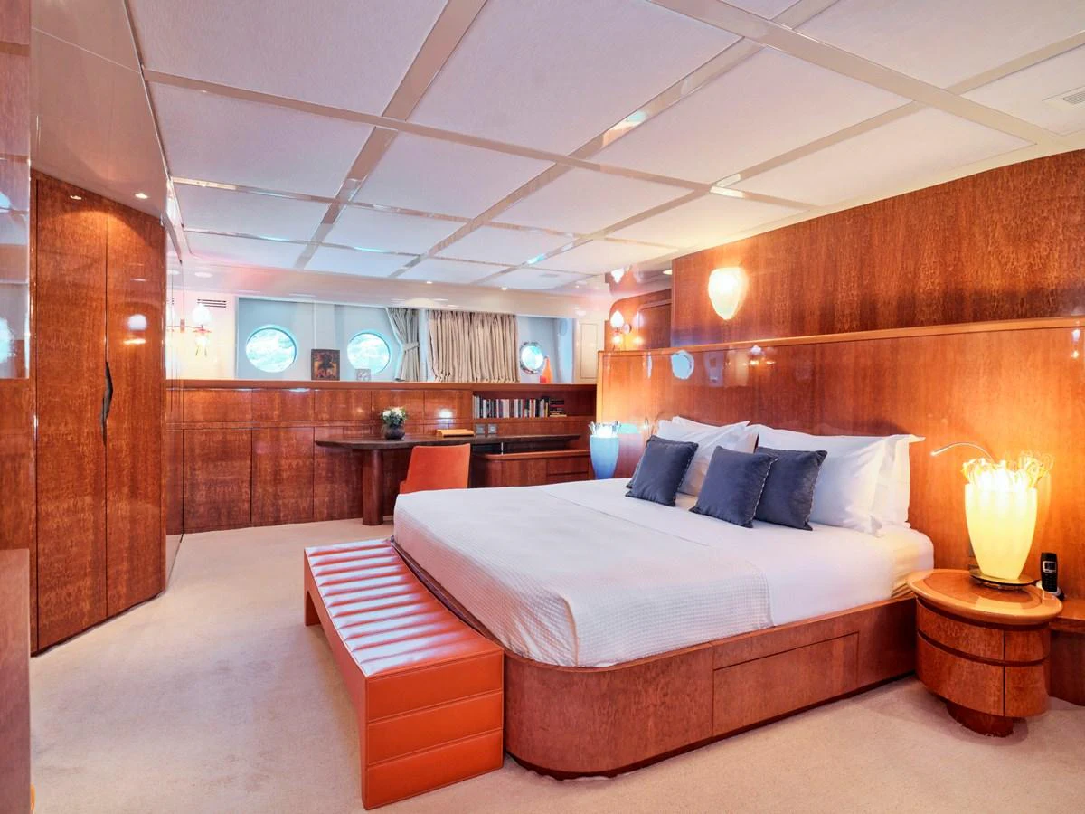 The master stateroom features luxurious wood paneling, a spacious bed, and elegant lighting. aboard CONDOR A Yacht for Sale