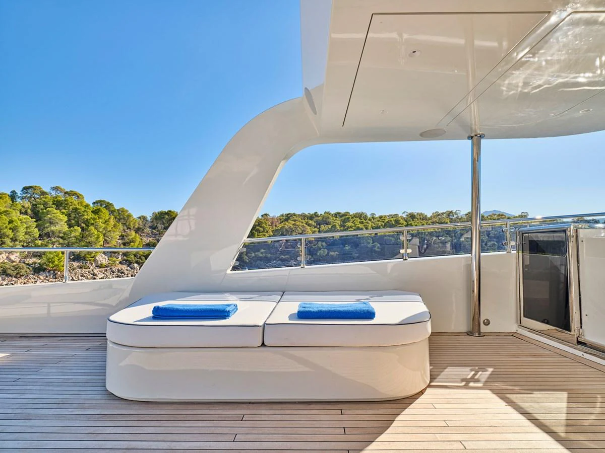 The aft deck features a sleek lounging area with plush cushions and a stunning view of the surrounding landscape. aboard CONDOR A Yacht for Sale