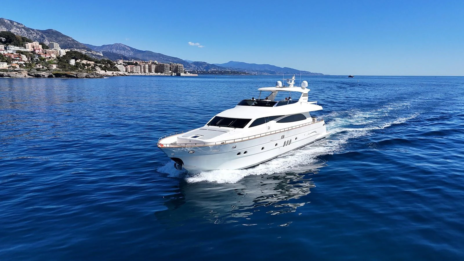 A sleek yacht cruises through calm, blue waters with a scenic coastal backdrop. aboard TIME OUT TOGETHER Yacht for Sale
